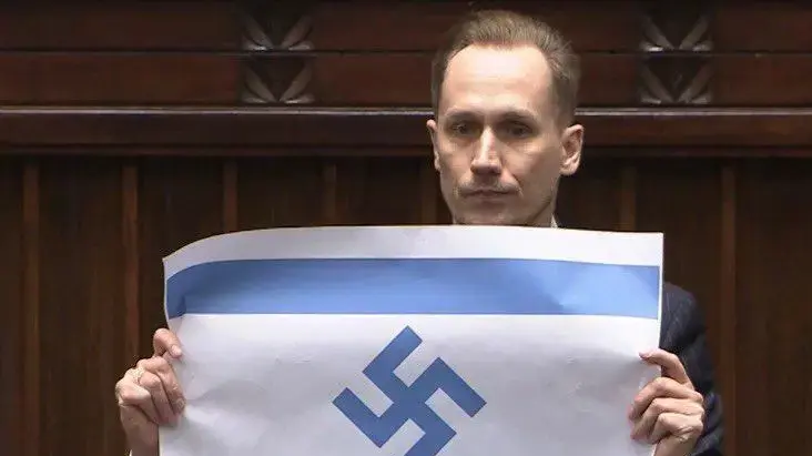 חבר פרלמנט פולני הניף את דגל ישראל עם צלב קרס במהלך דיון בפרלמנט ביום השואה, 14 באפריל 2026 חבר פרלמנט פולני הניף את דגל ישראל עם צלב קרס במהלך דיון בפרלמנט ביום השואה, 14 באפריל 2026