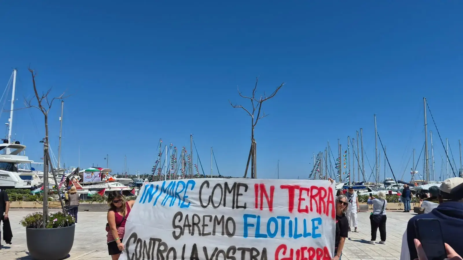 שלט: "In mare come in terra saremo flotille contro la vostra guerra" (באיטלקית: "בים כמו ביבשה, נהיה ציים נגד המלחמה שלכם"), נמל סירקוזה בסיציליה שלט: "In mare come in terra saremo flotille contro la vostra guerra" (באיטלקית: "בים כמו ביבשה, נהיה ציים נגד המלחמה שלכם"), נמל סירקוזה בסיציליה