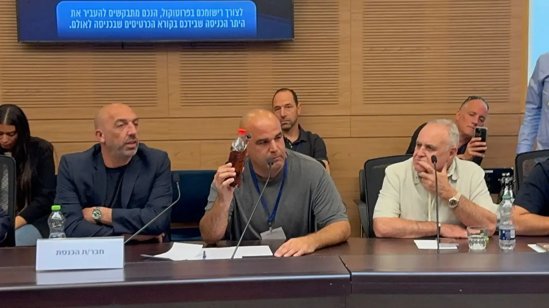 יריב בן עמי, מייסד אירגון עד כאן, מציג בקבוק עם דלק, שכמוהו עברייני הפרוטקשן תולים בכניסה לעסקים כסימן לכך שצריך לשלם להם דמי חסות