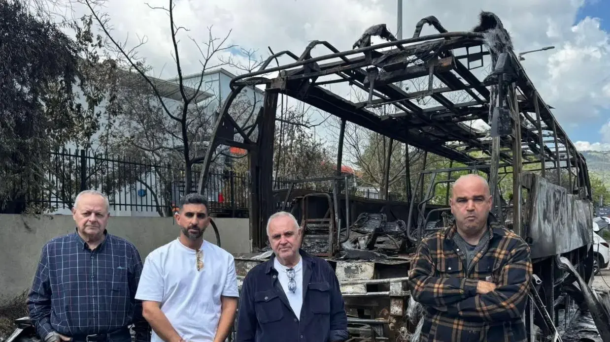 משפחת סגל ובן עמי (מימין) ליד אוטובוס החברה שהוצת בחודש שעבר. 
