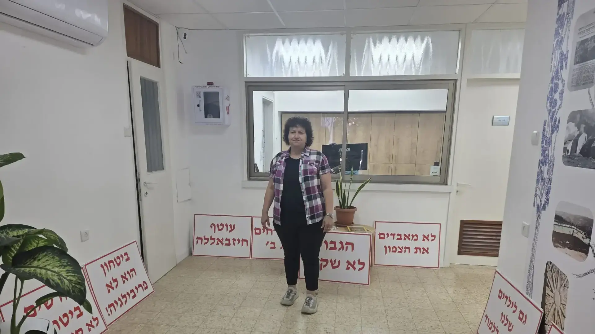נעמי בכור בפתח משרדה עם שלטי ההפגנה נעמי בכור בפתח משרדה עם שלטי ההפגנה