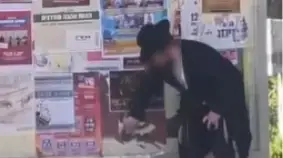 אדם חרדי מסיר מודעות עם תמונות של נשים, ערד