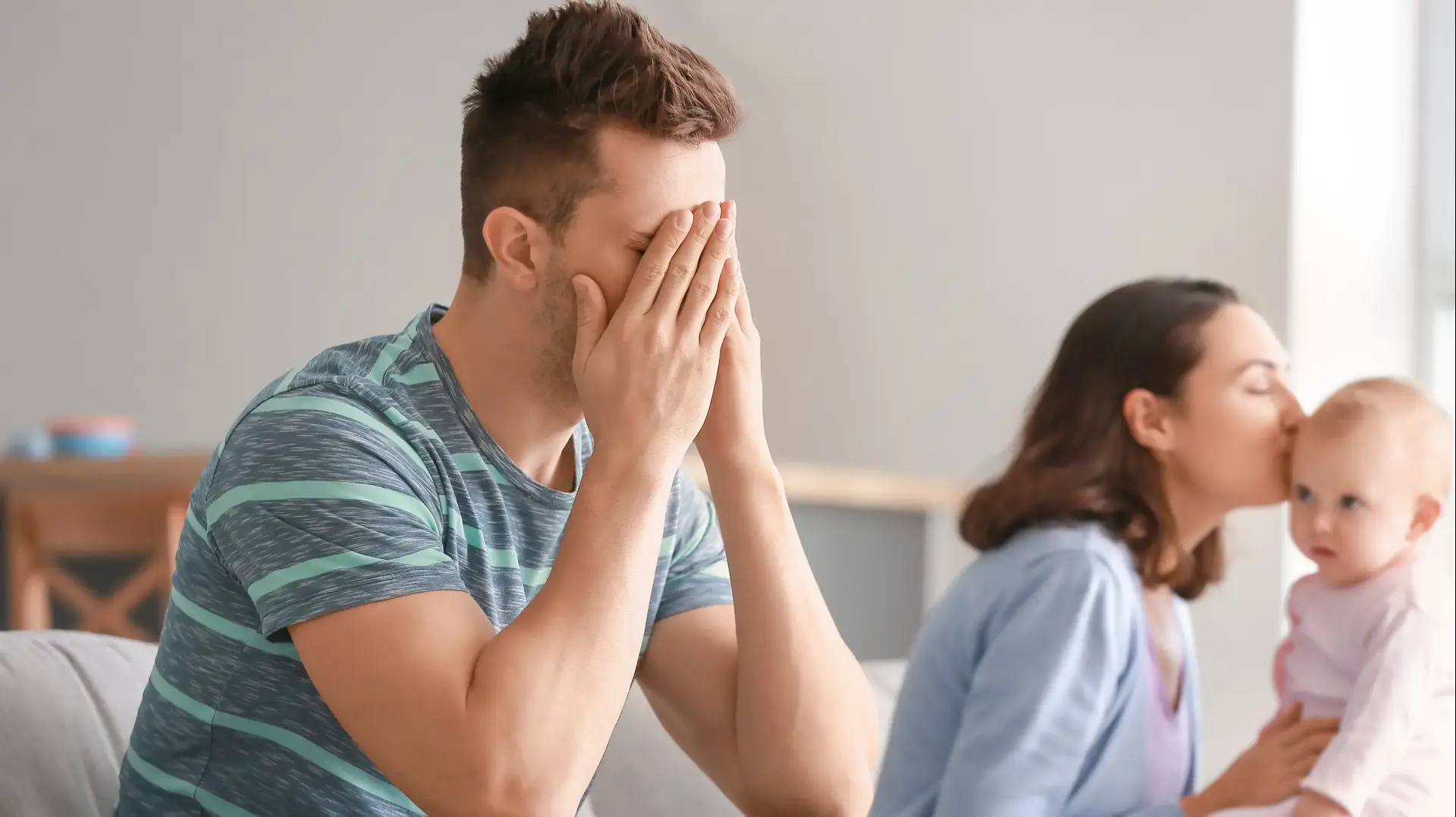 אבא עצוב ליד אמא מנשקת תינוק אבא עצוב ליד אמא מנשקת תינוק