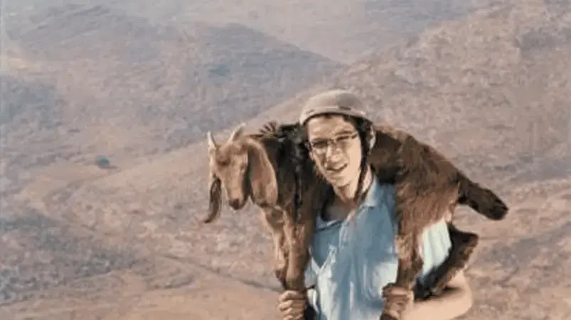 צעיר בעל משקפיים, כיפה ופאות, בחולצה תכולה ונושא גדי צעיר בעל משקפיים, כיפה ופאות, בחולצה תכולה ונושא גדי