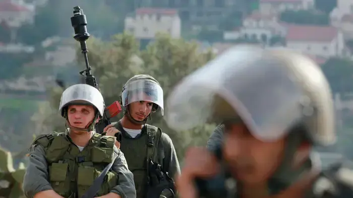 כוח מג''ב משקיף על מפגינים פלסטינים בזמן הפגנה נגד בניית גדר ההפרדה בניעלין