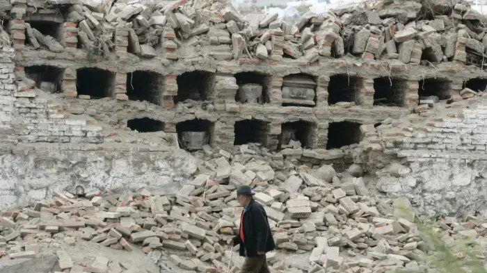 גבר הולך ליד בית קברות בקונספסיון שנהרס ברעידת האדמה בצ'ילה