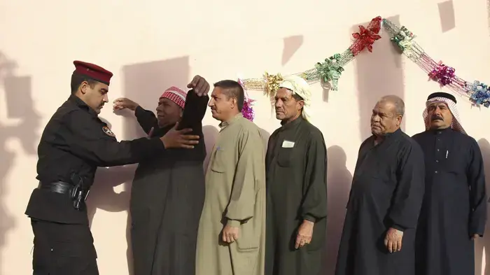 חייל בודק גברים בתור להצביע בבחירות בעירק