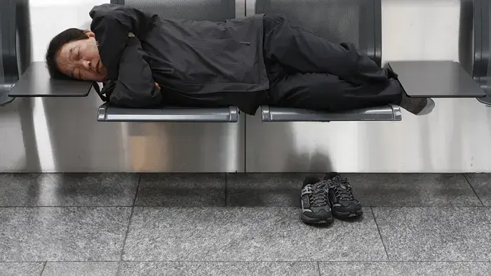 נוסע נח על מושבים ריקים בטרמינל נטוש בציריך, שוויץ