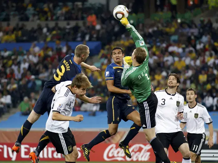 שוער נבחרת גרמניה מנואל נוייר הודף כדור מול שחקני אוסטרליה טים קייהיל, קרייג מור