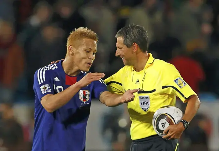 השופט הבלגי פרנק דה בליקר מתווכח עם קשר נבחרת יפן קייסוקה הונדה