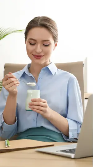 אישה במשרד אוכלת יוגורט. ShutterStock