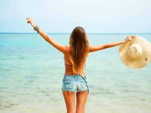 אישה צעירה במכנסי ג'ינס קצרים בחוף הים