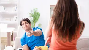 גפר צופה בטלוויזיה ובת זוגו מסתירה לו (ShutterStock)