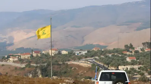 משקיפים של האו"ם חולפים על פני דגל של חיזבאללה בעיירה חיאם, דרום לבנון, 28 ביולי 2020 (רויטרס)