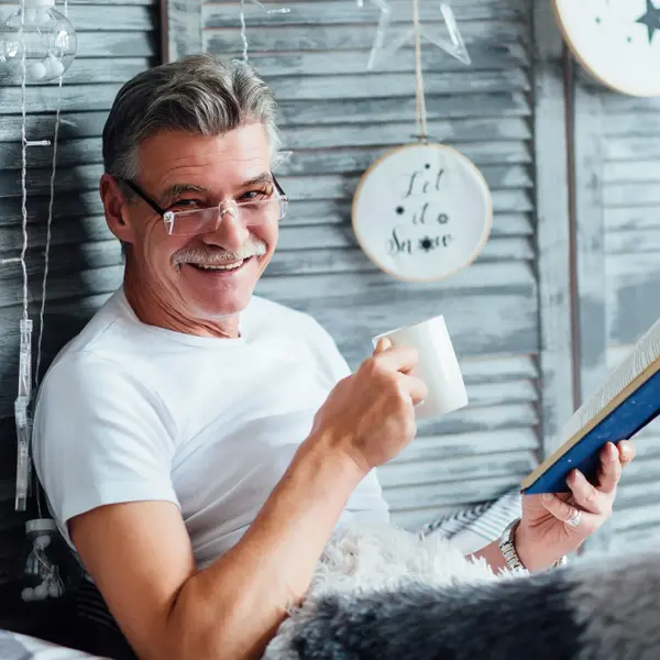 איש מבוגר עם כוס תה קורא ספר. ShutterStock