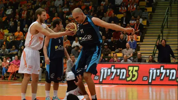 פורוורד הפועל אילת אלישי כדיר (למעלה, ימין) מעל שחקן עירוני נס ציונה מיטשל וואט (למטה) פורוורד הפועל אילת אלישי כדיר (למעלה, ימין) מעל שחקן עירוני נס ציונה מיטשל וואט (למטה)