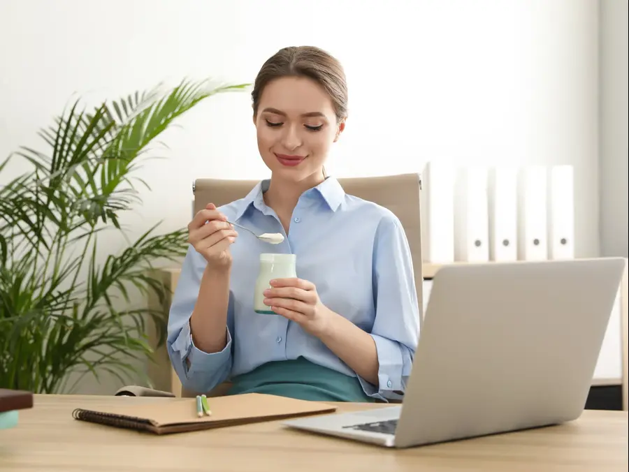 אישה במשרד אוכלת יוגורט. ShutterStock