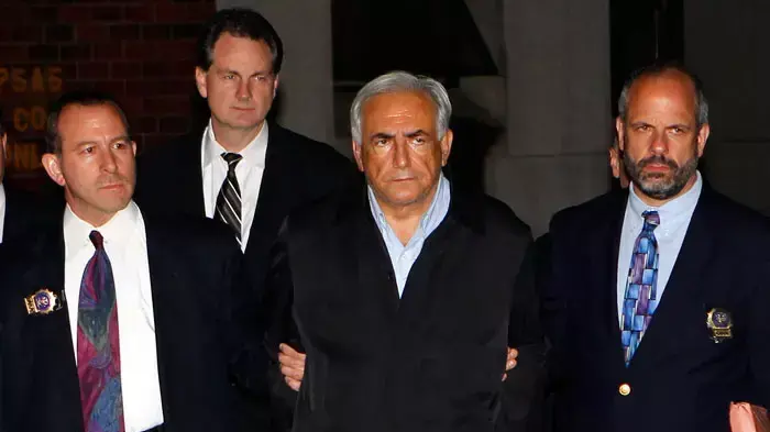 דומיניק שטראוס-קאהן, יו"ר קרן המטבע הבינלאומית החשוד באונס, מובל אזוק באזיקים אל מחוץ לתחנת המשטרה בהארלם, ניו יורק, 15 במאי 2011 דומיניק שטראוס-קאהן, יו"ר קרן המטבע הבינלאומית החשוד באונס, מובל אזוק באזיקים אל מחוץ לתחנת המשטרה בהארלם, ניו יורק, 15 במאי 2011