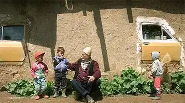 ילדים וסבם יושבים מחוץ לביתם בקוסובו