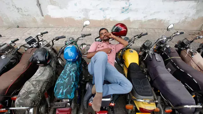 גבר נח על אופנוע בעיר קראצ'י בפקיסטן