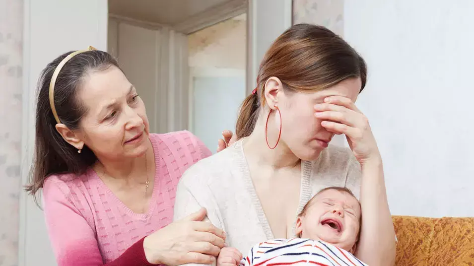 אם מחזיקה תינוק ובוכה ואישה מנחמת אם מחזיקה תינוק ובוכה ואישה מנחמת