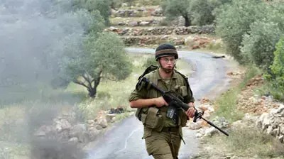 חייל צהל עובר ליד צמיגים בוערים בכפר בילעין חייל צהל עובר ליד צמיגים בוערים בכפר בילעין