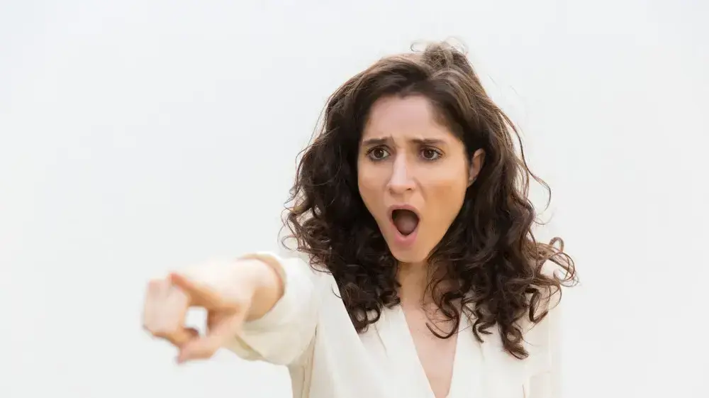 אישה מפנה אצבע בהבעה מאשימה אישה מפנה אצבע בהבעה מאשימה