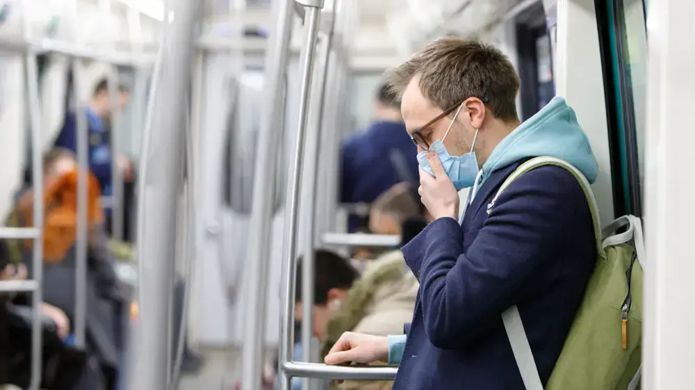 אדם עם מסיכה משתעל ברכבת התחתית אדם עם מסיכה משתעל ברכבת התחתית
