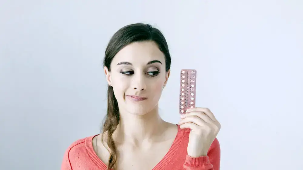 אישה מחזיקה חפיסת גלולות למניעת היריון אישה מחזיקה חפיסת גלולות למניעת היריון