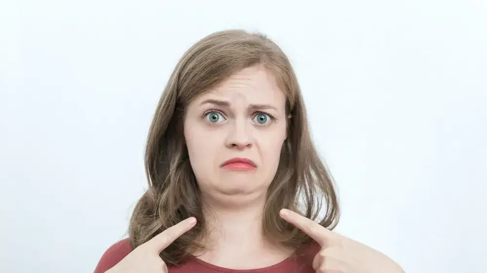 אישה מצביעה על הסנטר שלה אישה מצביעה על הסנטר שלה