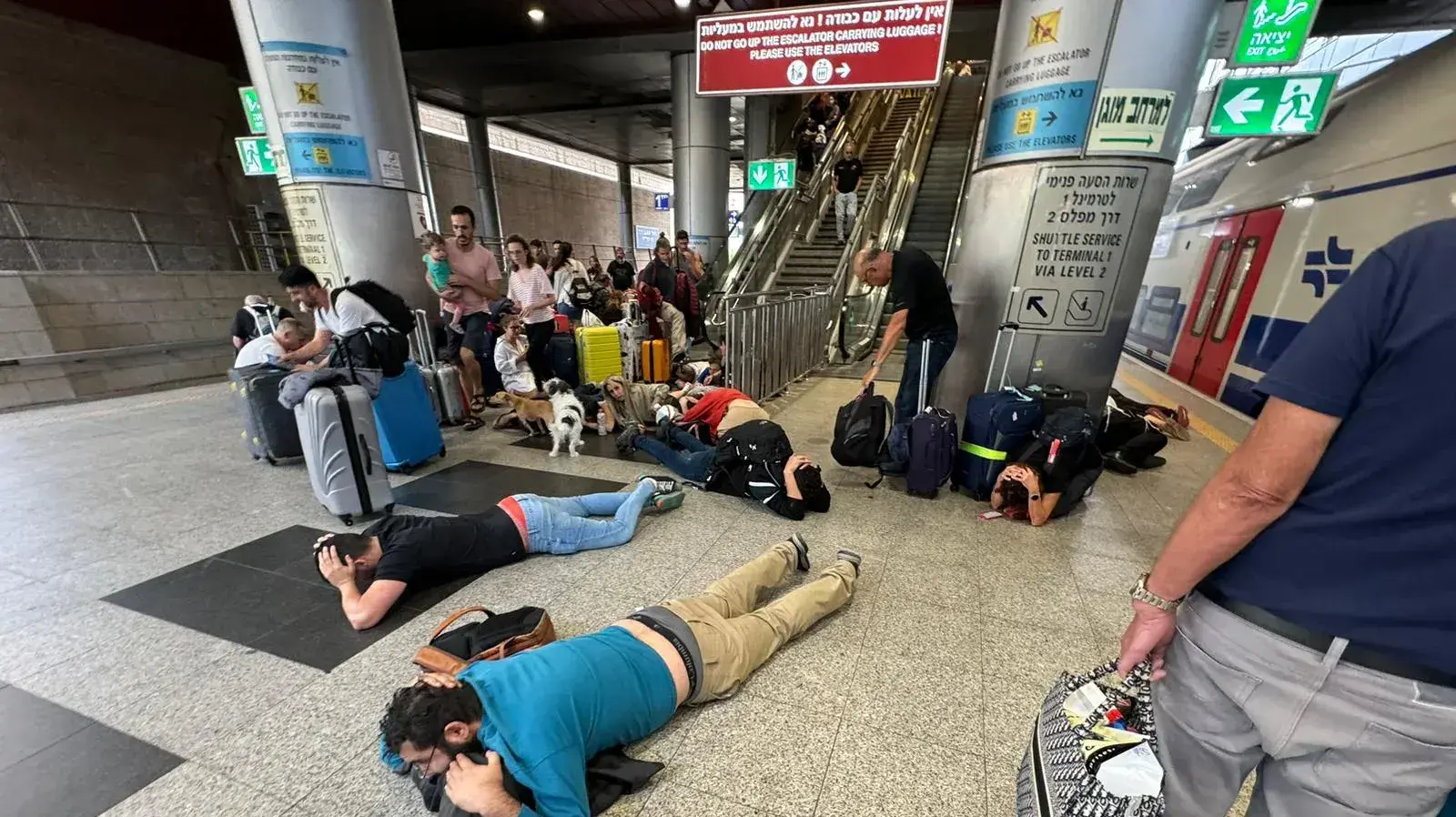 נוסעים בתחנת הרכבת שוכבים על הרצפה בעת אזעקה, נתב"ג, 9 באוקטובר 2023 נוסעים בתחנת הרכבת שוכבים על הרצפה בעת אזעקה, נתב"ג, 9 באוקטובר 2023