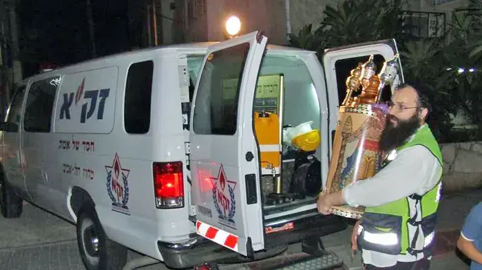ספר התורה שהוצל על ידי מתנדבי זק"א מוכנס לאמבולנס זק"א