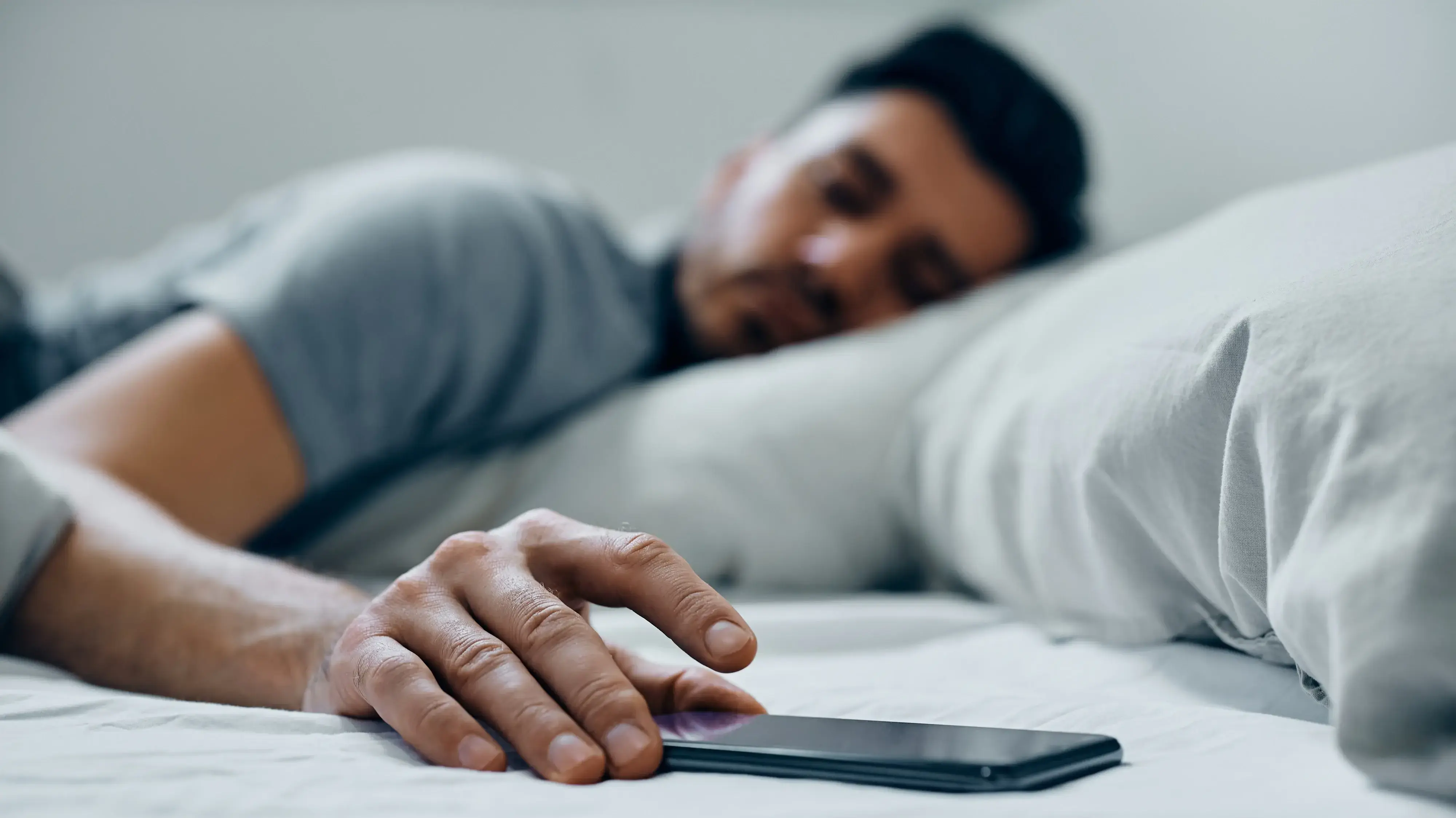 גבר עם טלפון נייד במיטה גבר עם טלפון נייד במיטה