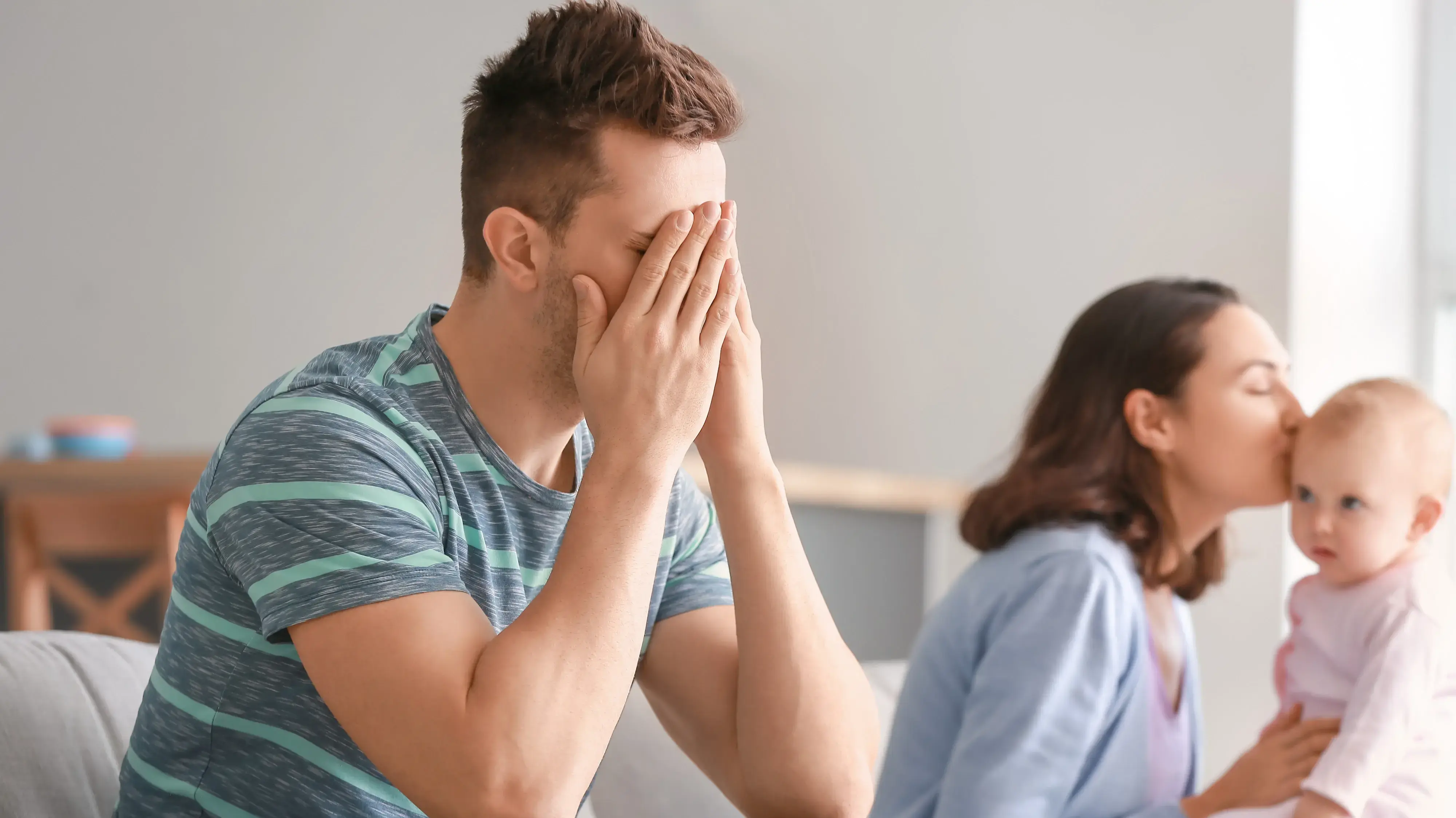 אבא עצוב ליד אמא מנשקת תינוק אבא עצוב ליד אמא מנשקת תינוק