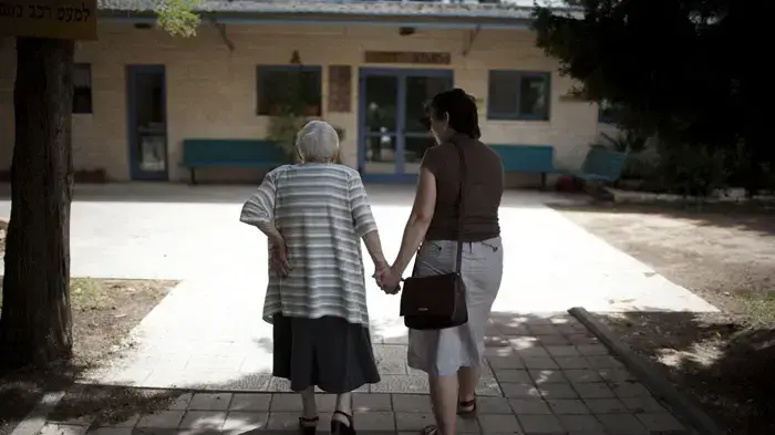 קשישה נעזרת במטפלת שלה בישוב קדומים שבשומרון קשישה נעזרת במטפלת שלה בישוב קדומים שבשומרון