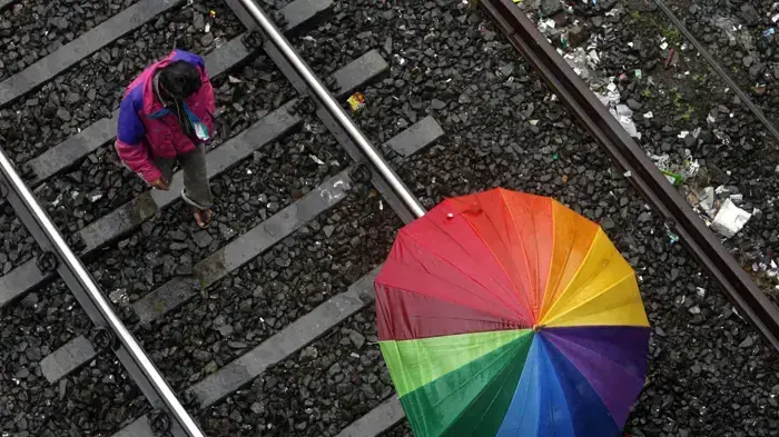 מטיילים מתהלכים על פסי רכבת במהלך גשמי מונסון במומביי