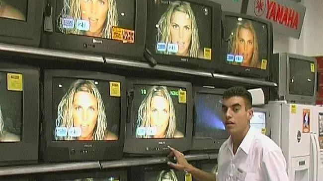 מוכר בחנות למוצרי חשמל מול מסכי טלויזיה מוכר בחנות למוצרי חשמל מול מסכי טלויזיה
